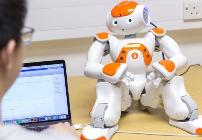 Technician programming robot on desk