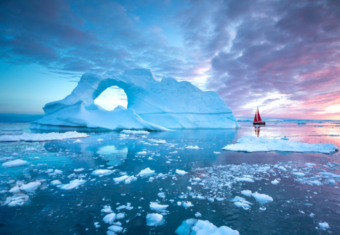 An Arctic scene showing an iceberg and small sail boat