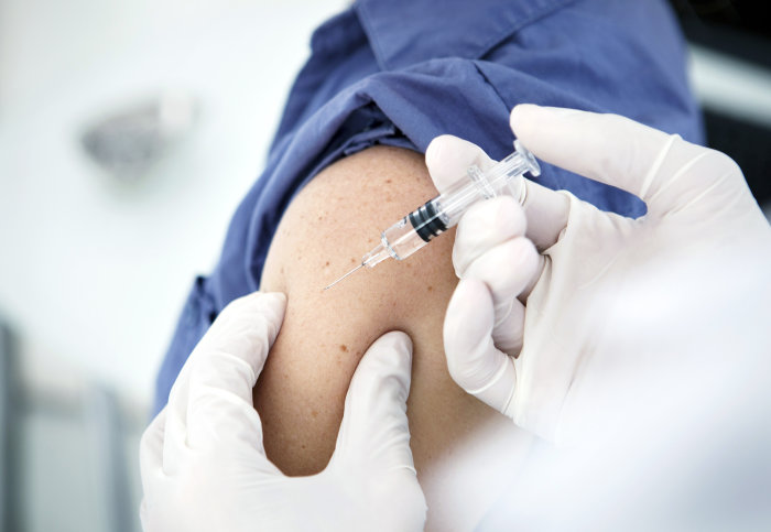 A patient receiving a flu jab in their upper arm