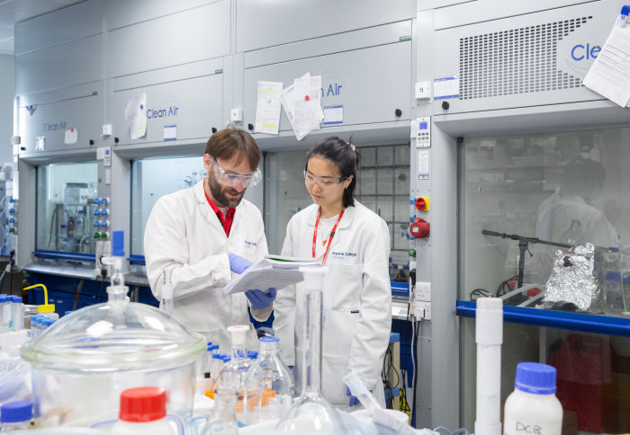 Two people wearing lab coats, standing in a lab.