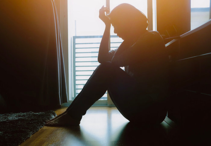 A woman sat on the floor, head in hands