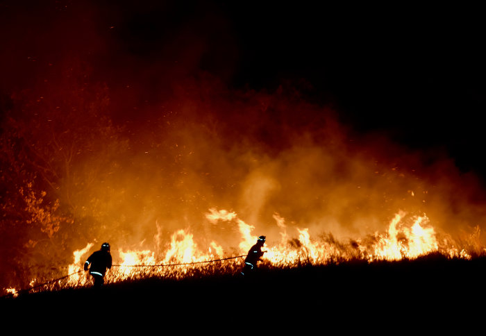 Two firefighters in front of a bushfire