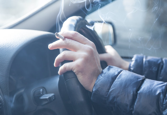 Man holding a cigarette in the car