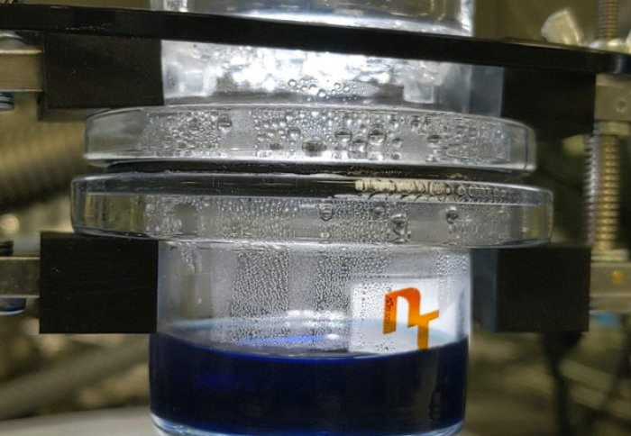 The photocatalysis reactor producing hydrogen gas, with organic semiconducting nanoparticles (blue ink) under a light source mimicking the solar spectrum