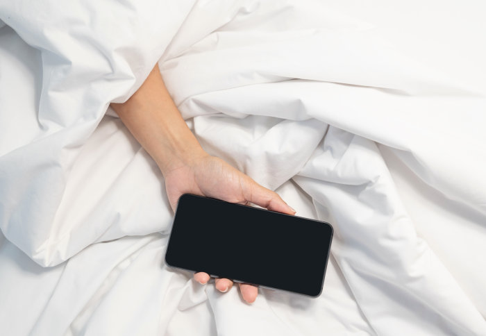 Hand holding a phone in bed
