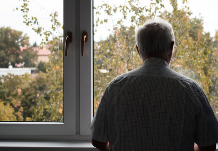 An elderly man looking out of a window