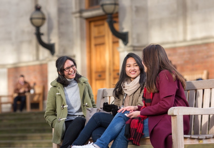 Three students sitting on a bench talking