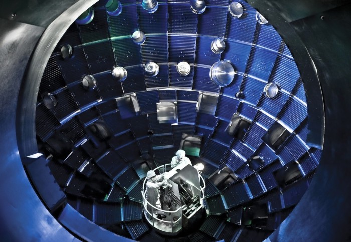 Scientists in white suits inside a metallic chamber