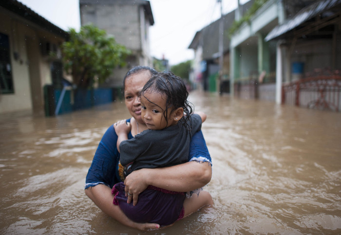 Woman carrying a child through floodwater