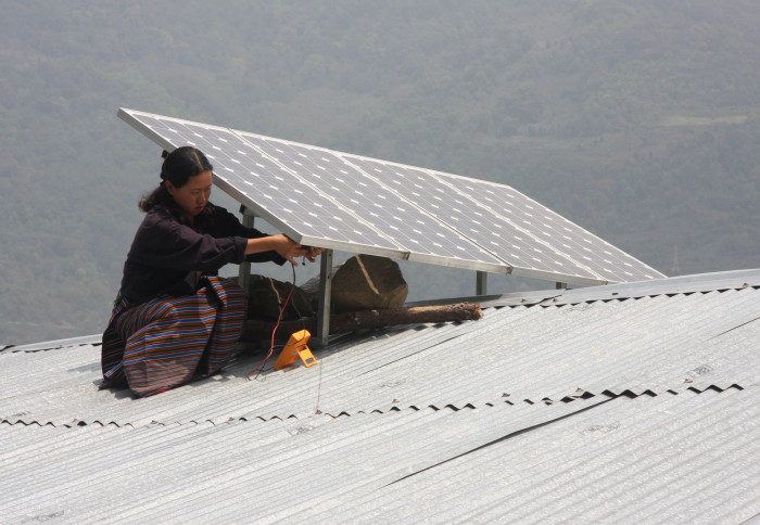 Woman on a roof installing a solar panel