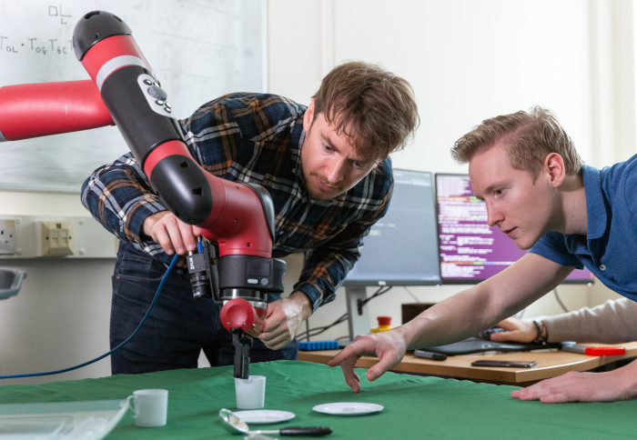 Two computing students working on a robot