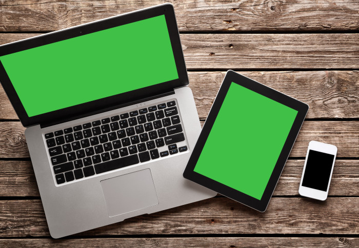 Open laptop with digital tablet and white smartphone. All with isolated screen on old wooden desk.