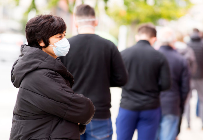 Woman queues in a line while wearing a mask