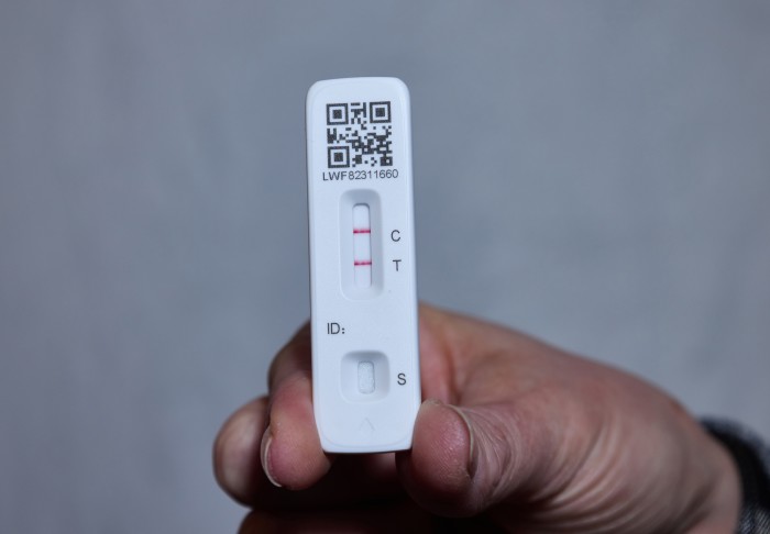 A person holds up a positive lateral flow test (LFT)