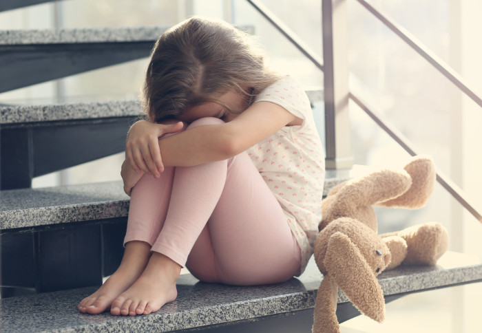 A young child looking sad in their home