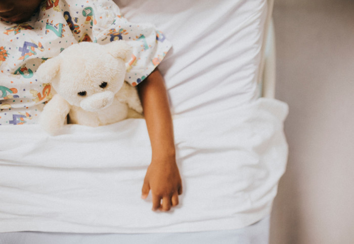 A child in a hospital bed with a teddy bear