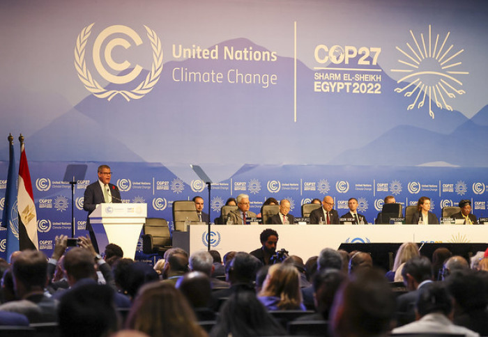 Negotiators at the COP27 conference centre sit behind a large desk, former COP President Alok Sharma speaks from a podium, backdrop reads: United Nations Climate Conference COP27 Sharm El Sheikh Egypt