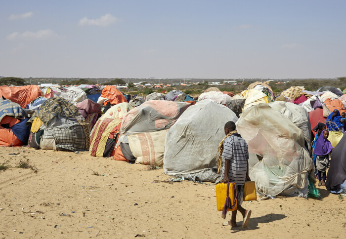 A person carries water containers past a displaced persons camp in Somalia.