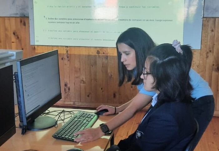 Catalina guiding a student through the Python workshop. They both look at a computer screen.