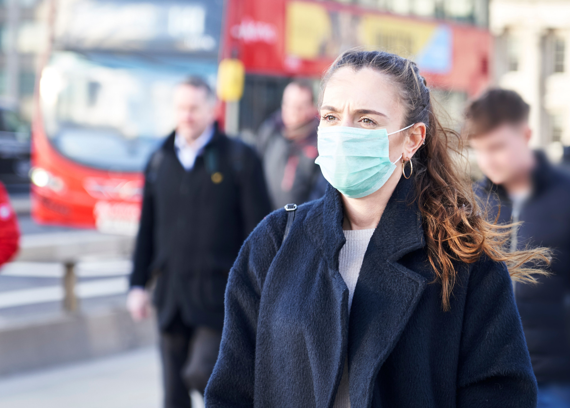 Woman wearing medical mask walks down London street