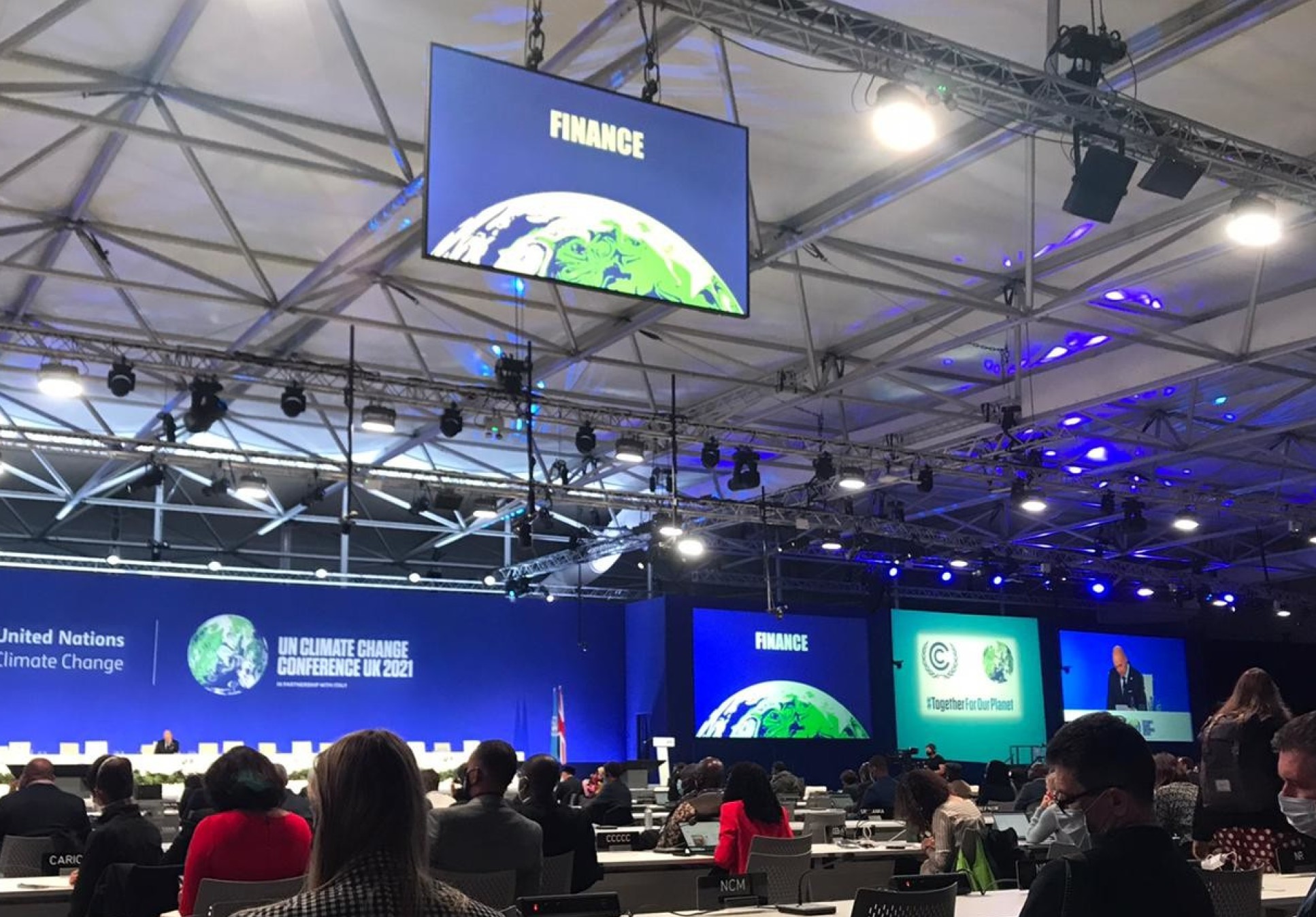 Plenary room at COP with 'Finance' written on a hanging board, and people sittign at desks