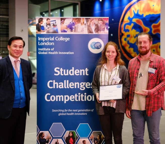 A photograph of judge Guangzhong with the two researchers behind Capta, holding their trophy.