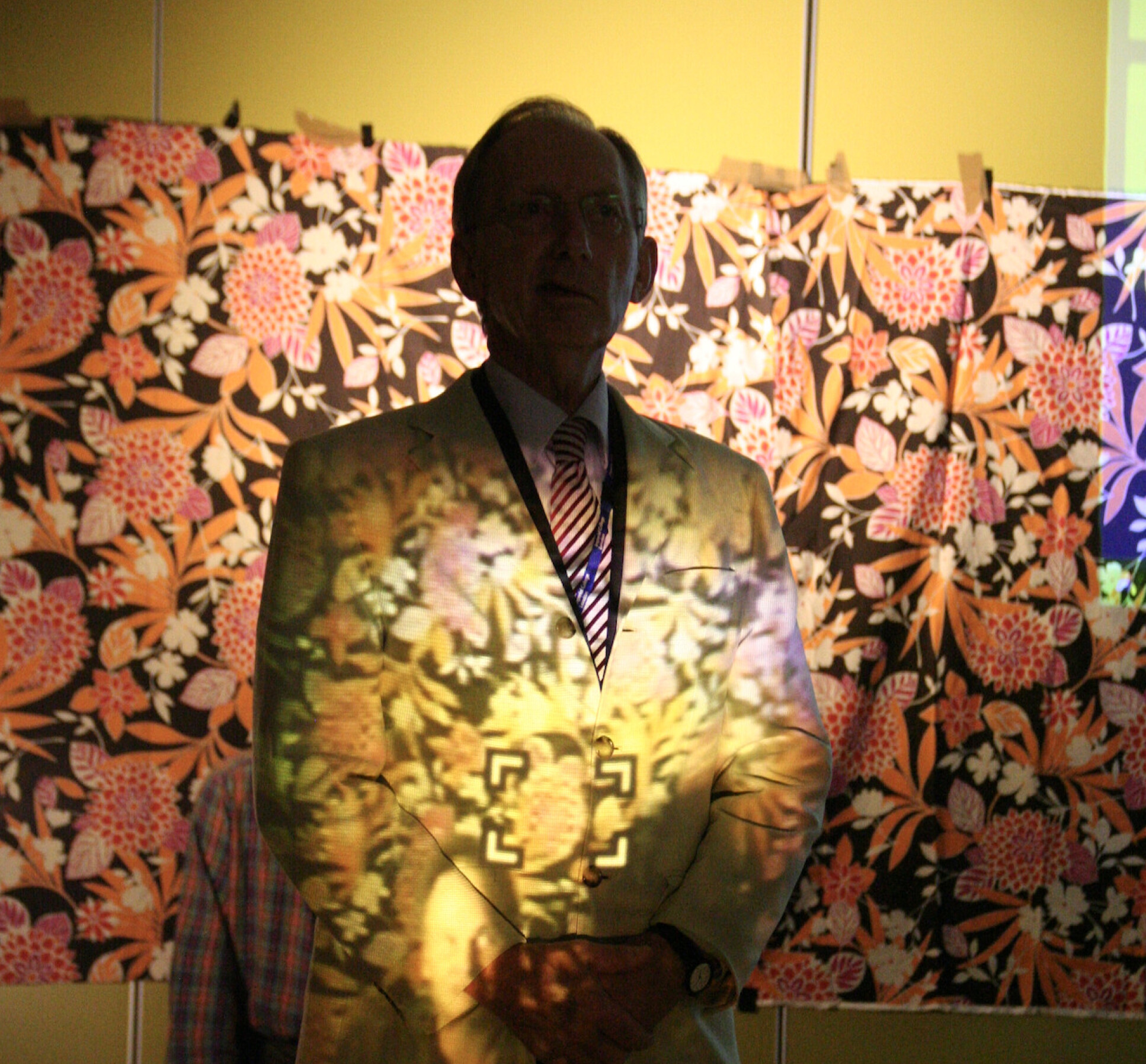 Pendry stands in front of a project, demonstrating how light still travels around him onto the screen behind him.