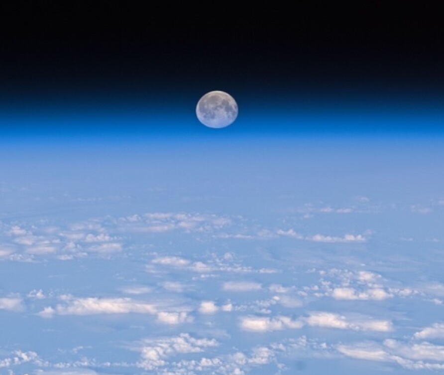 Image showing the Earth's atmosphere and the moon in the background.