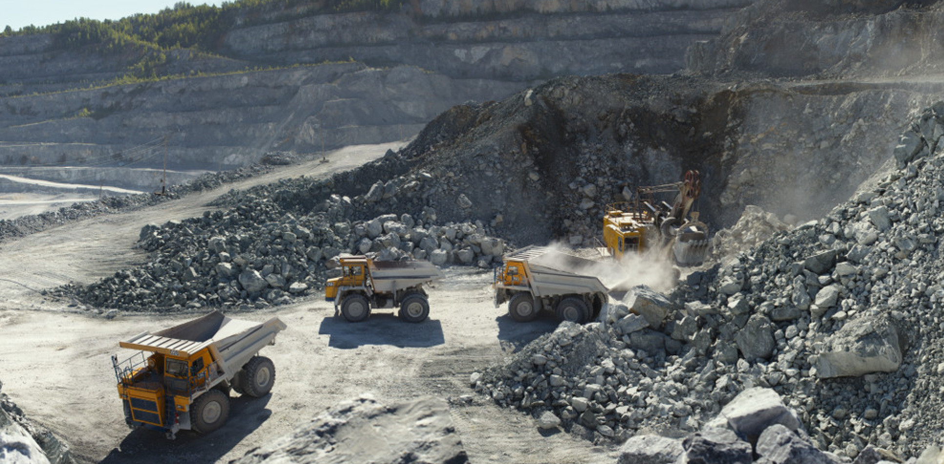 Photo of excavator and heavy mining dump trucks in a limestone quarry, loading of stone ore, industrial panorama.