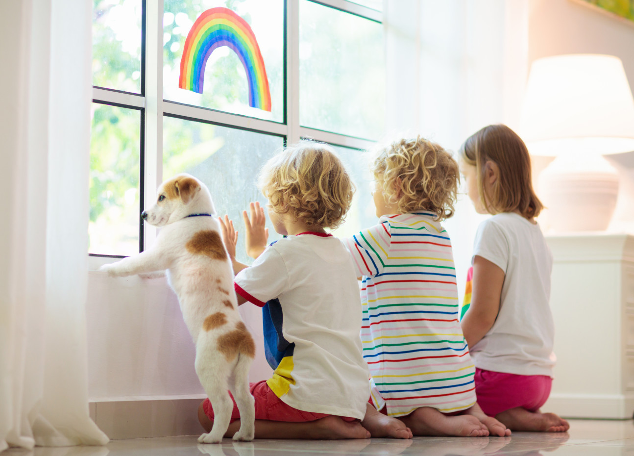 Children and a dog looking out of a bedroom window
