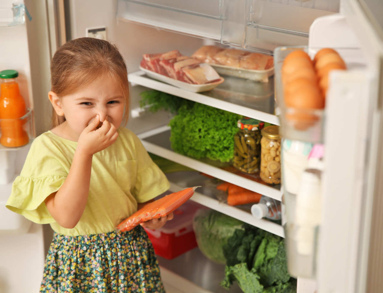 little girl holding nose next to a fridge to indicate that food inside has gone off