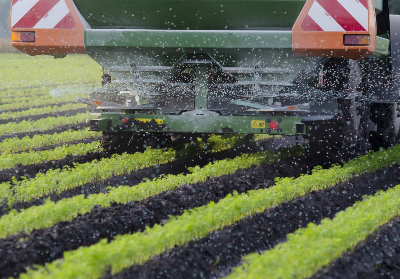 A tractor spreading ammonia on a field