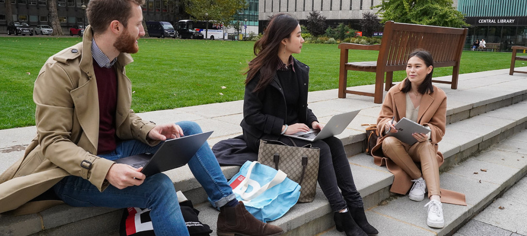 Three students sitting on the Queen's Lawn studying