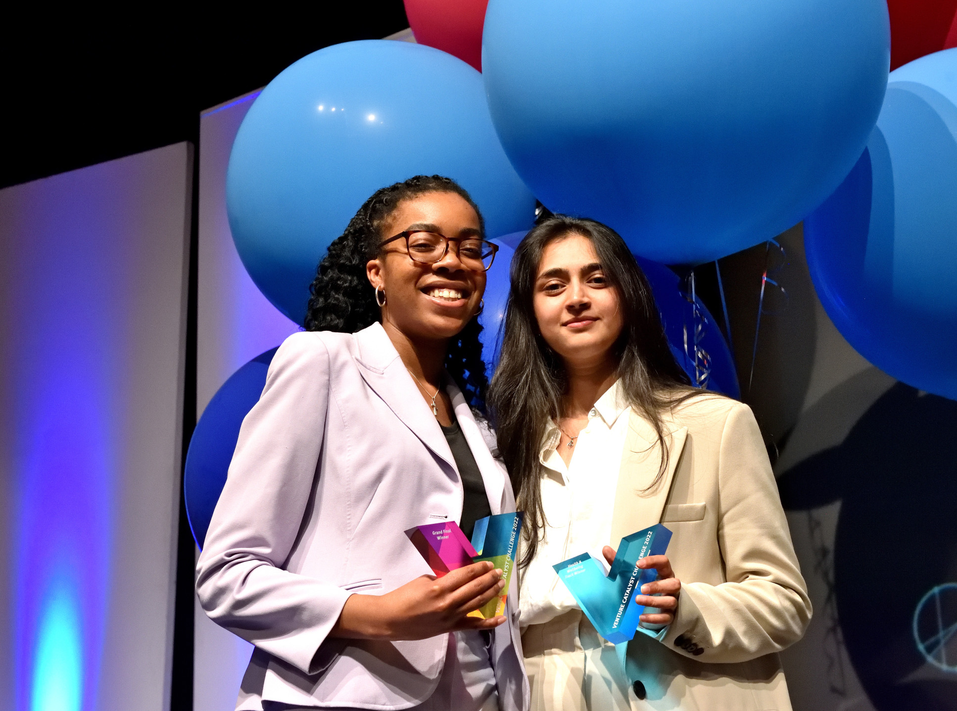 Two students holding a trophy on a stage