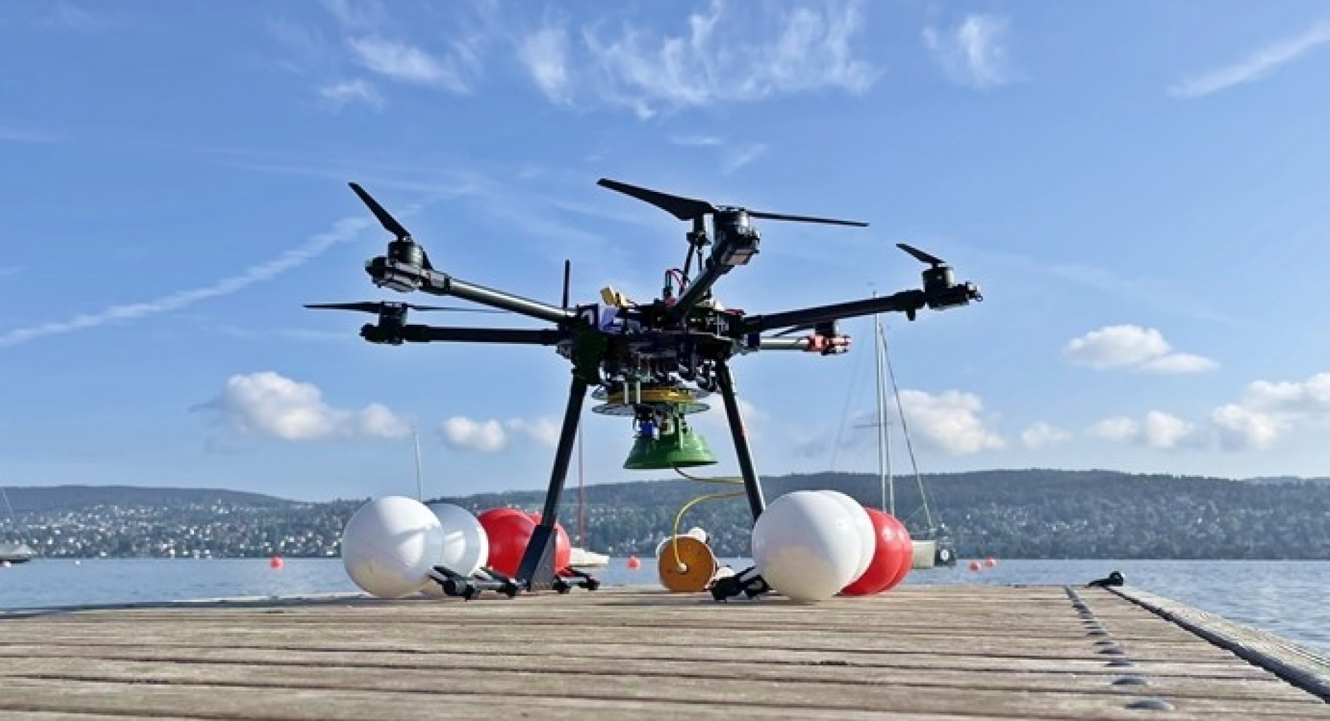 Photo from behind drone shows it poised for take-off. In the background is Lake Zurich.