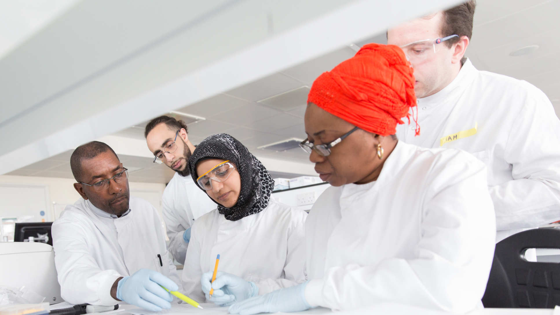 Dr Wayne Mitchell with four students at a laboratory work bench