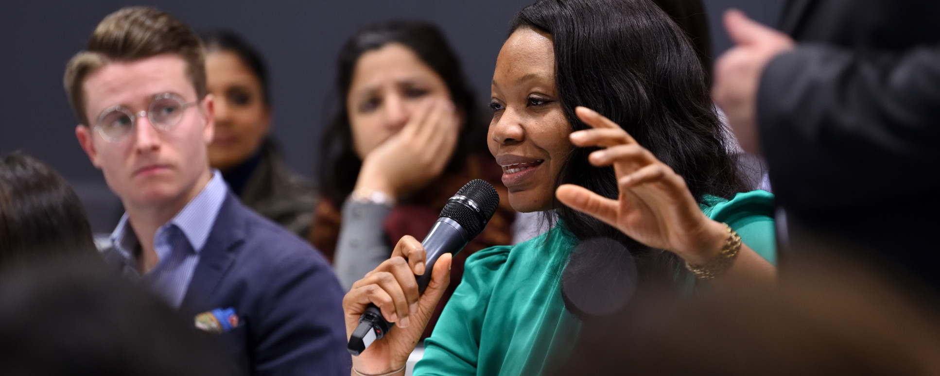 Woman smiles as she speaks into a microphone at a previous healthcare event