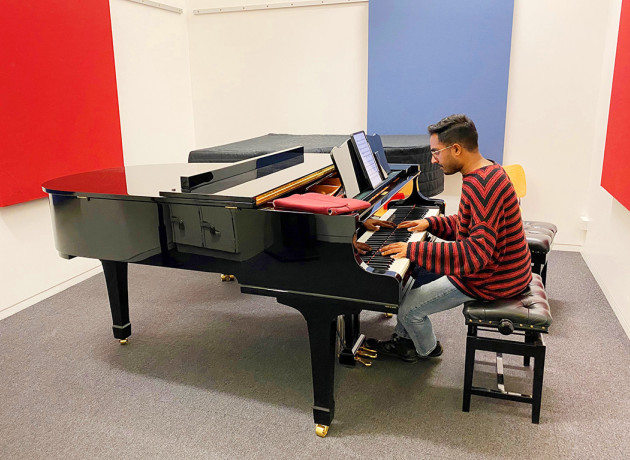 A student playing a grand piano