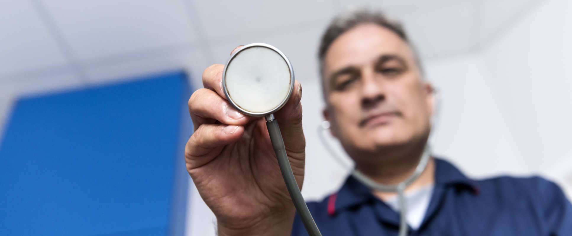 Nurse with stethoscope leans to camera
