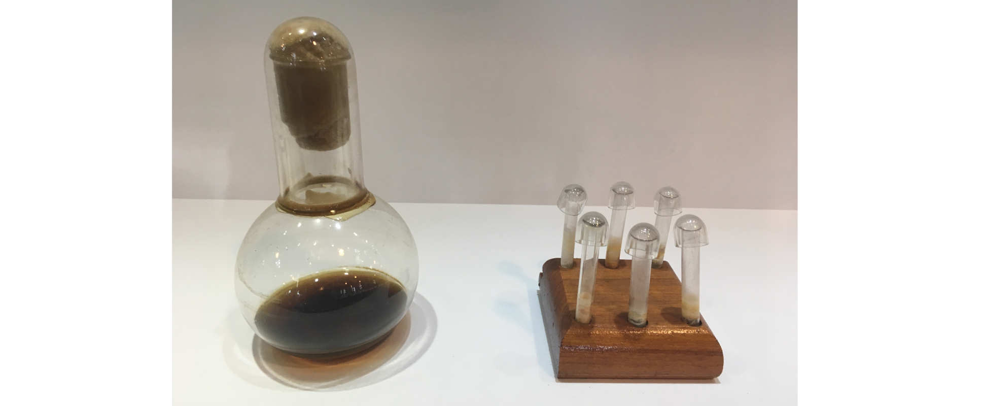 Glass flask with dark brown liquid and vials