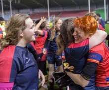 Two women rugby players embrace at Varsity