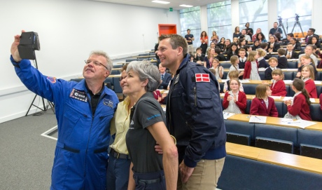 Four astronauts taking a selfie in a room of schoolchildren