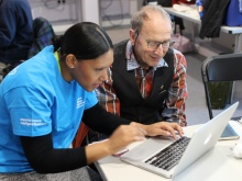 A student volunteer helps a resident with his laptop