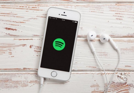 An iPhone with headphones plugged in and the Spotify symbol on the screen.