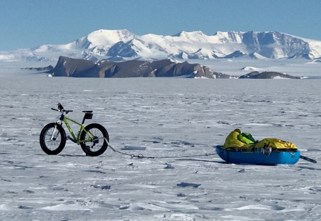 A bicycle and sled on a vast ice sheet in Antarctica with mountains in the background.