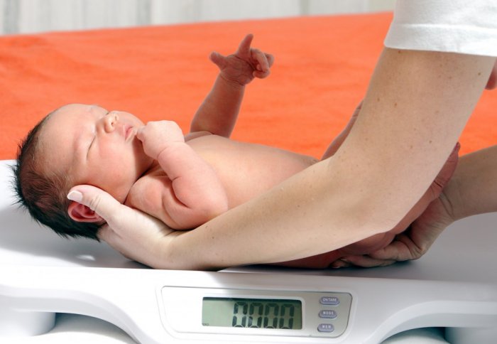 A baby being placed on scales.