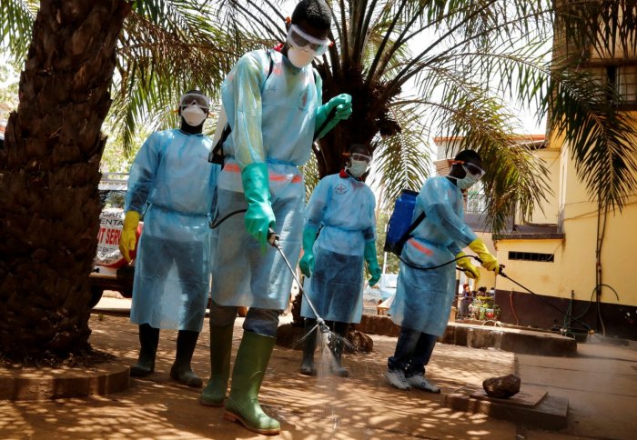 Volunteers for the Red Cross Society of Guinea disinfect a hospital in Conakry
