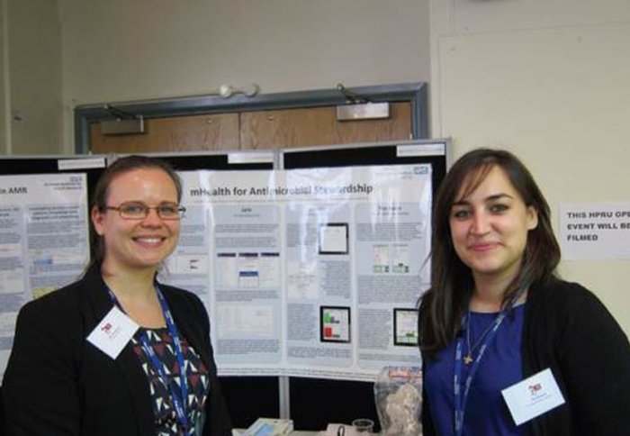 Researchers Mia Mosavi and Elita Jauneikaite display posters on bacteria at the HPRU open day
