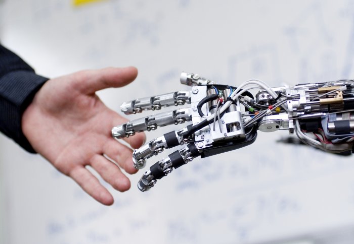 A human hand touching a robot hand