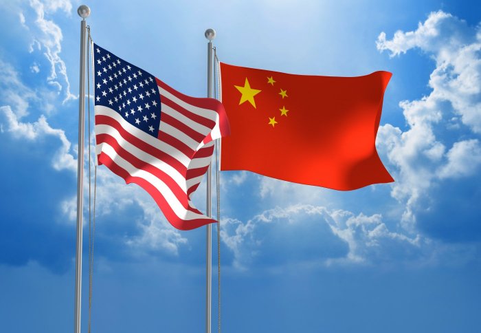 United States and Chinese flag fly together in the blue sky